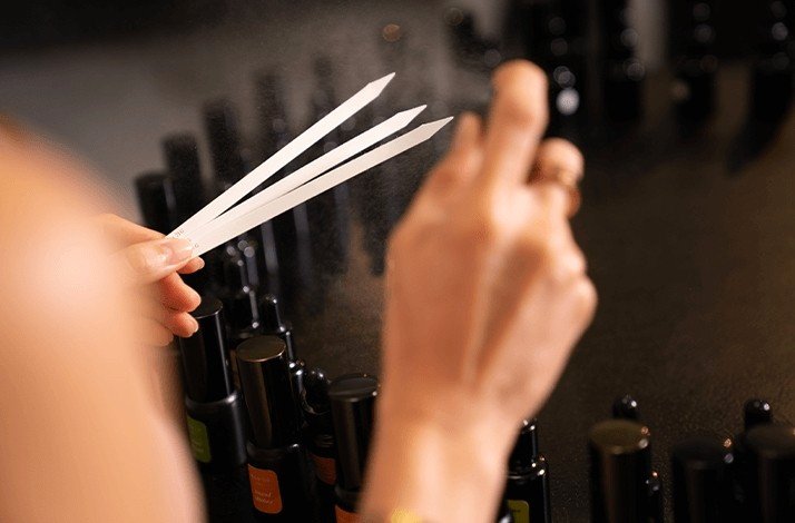A woman spraying her fragrance on the paper sticks.