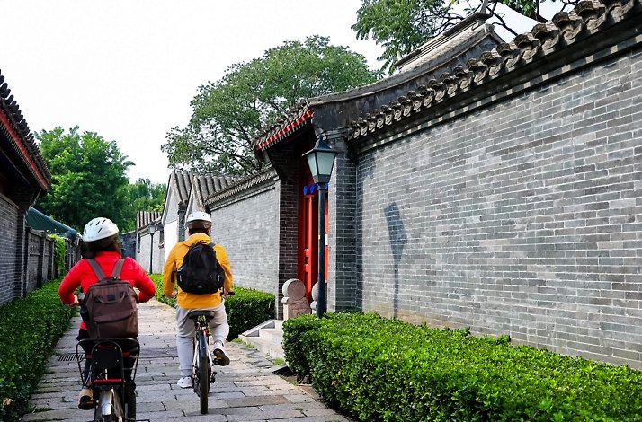 People cycling through a hutong in Beijing, China.
