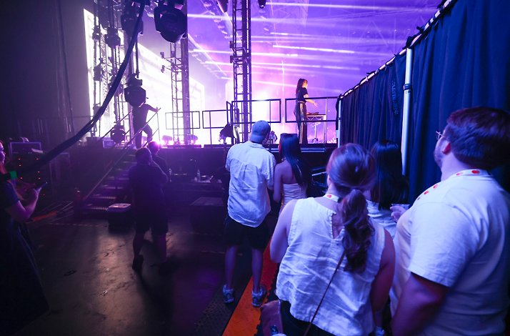 Guests viewing an artist performing at a DJ booth on stage from an exclusive side-of-stage vantage point at AO Live Presents, Melbourne Park.