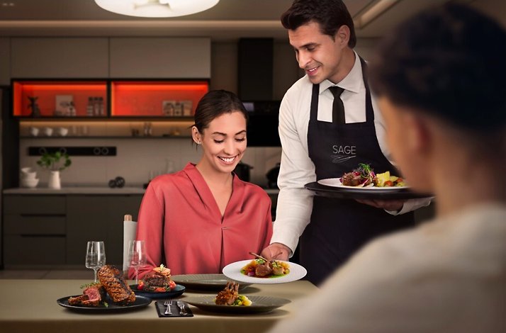 A The Sage Experience butler serving meals to a couple.