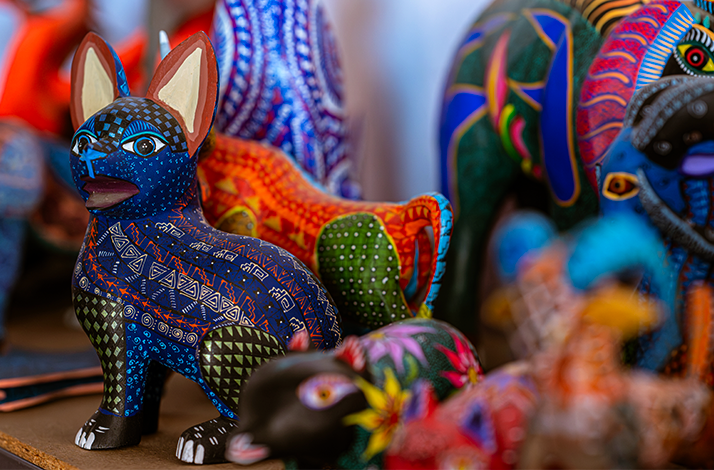 A display of several colorful, hand-painted animal figurines, with a blue and white patterned creature in the foreground.