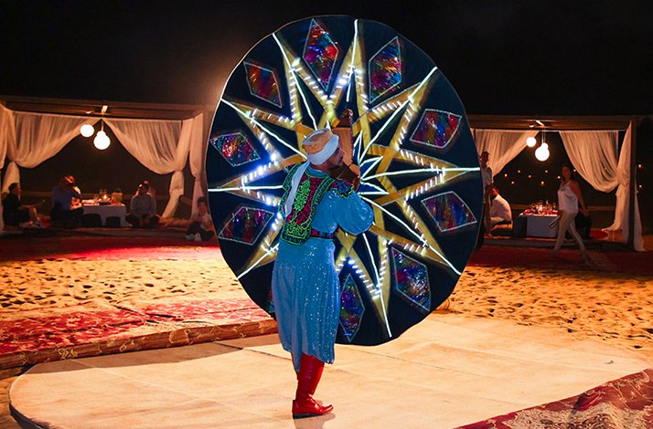 Performer showcasing a LED-lit tanoura dance at a desert camp.