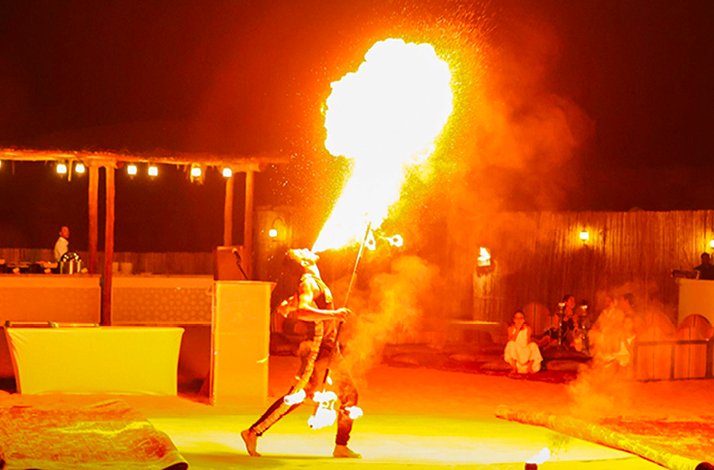Performer doing a fire-breathing act at a desert camp.