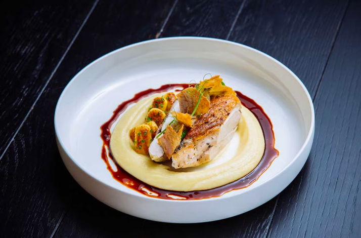 Pan-seared chicken over potato puree with rich reduction sauce at Superblue Miami.