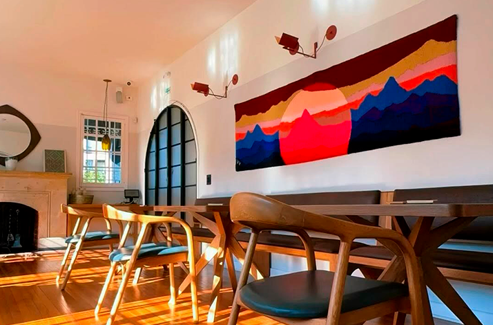 Interior of the restaurant showcasing modern design elements and artisan details, including a colorful wall tapestry that adds warmth to the space