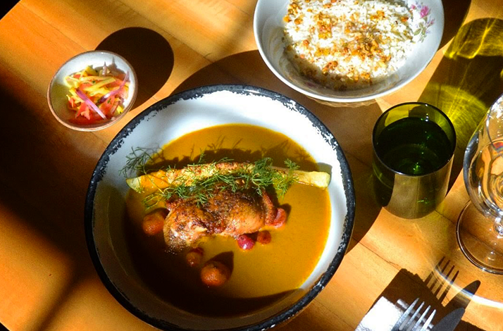 A beautifully plated dish featuring protein, vegetables, and side accompaniments, presented under natural light that enhances its colors