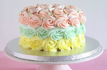 Cake with 3 layers of piping in yellow, green and pink buttercream frosting and sprinkled with edible elements