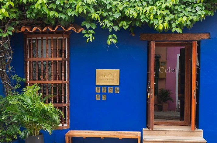 The cobalt-blue restored-house facade of Celele restaurant in the Getsemani neighbourhood of Cartagena, Colombia, with the Celele nameplate beside an open doorway framed by greenery