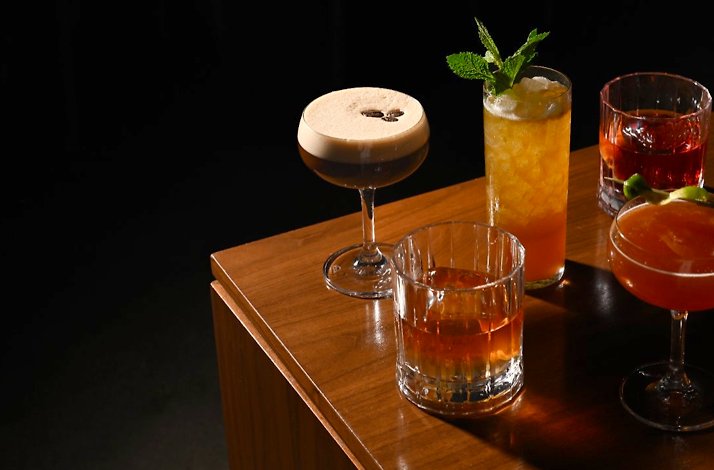 A selection of handcrafted cocktails served at Trade on a wooden table.